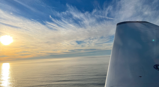 image of water, sky with clouds, airplane tail