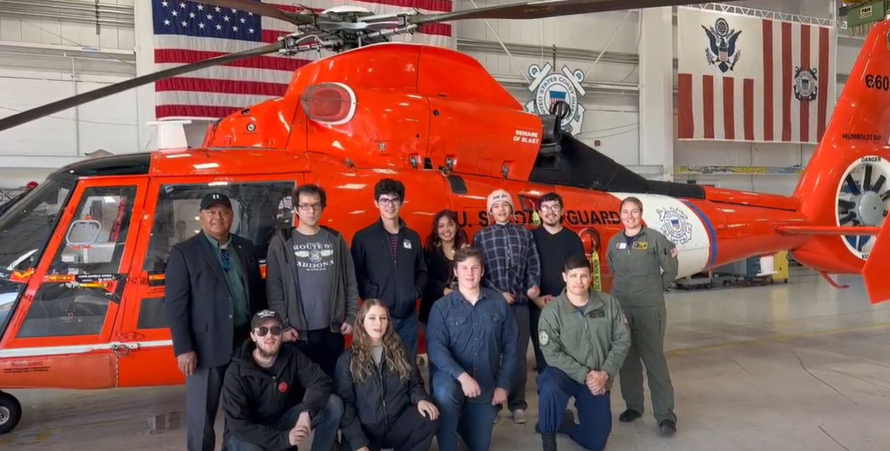 image of people standing next to Coast Guard helicopter