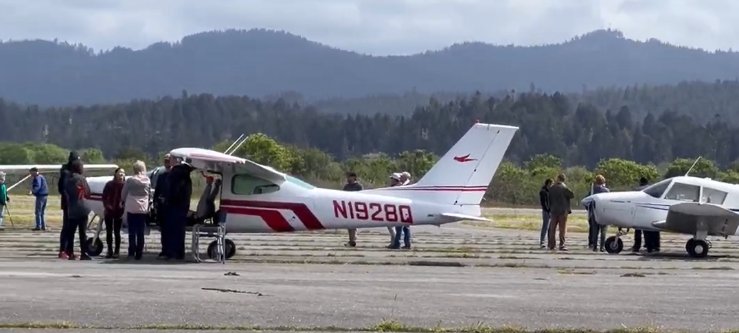 image of people around 2 small aircraft